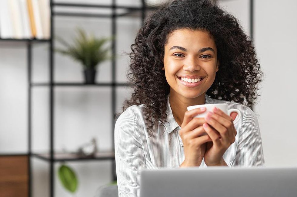 Happy woman with coffee/tea starts her workday early in the summer