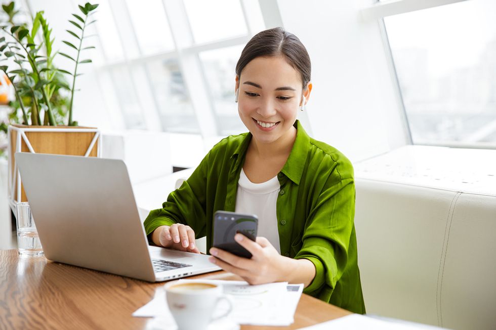 Woman on phone and laptop quantifies her experience on her resume