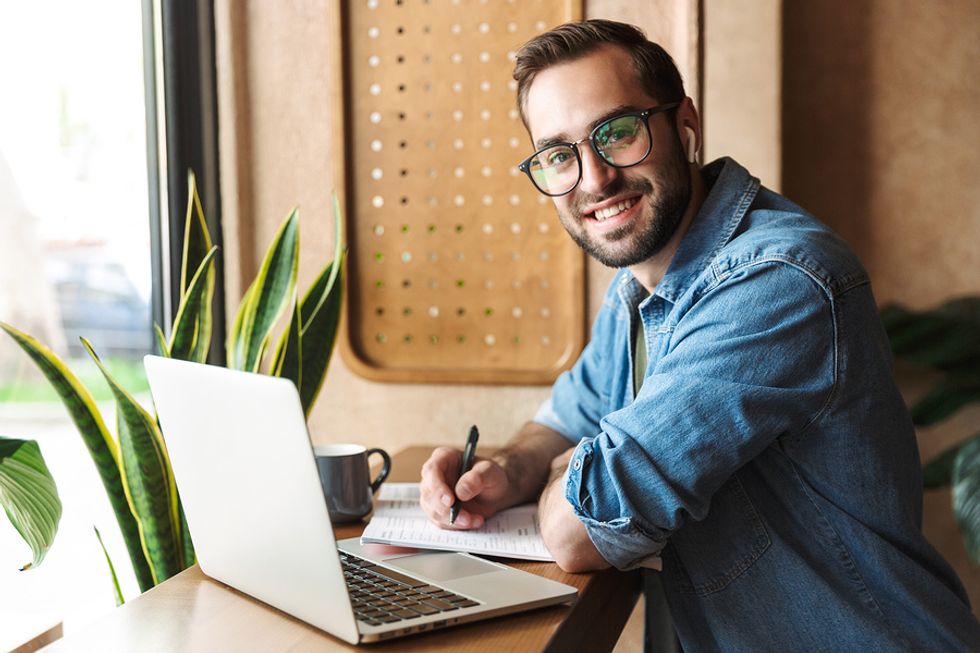 Man on laptop writes down quantifiable accomplishments on his resume