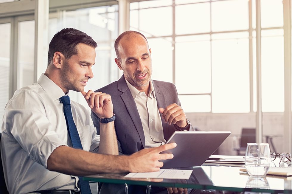 Male leader uses his leadership skills by giving constructive feedback to a member of his team during a work meeting