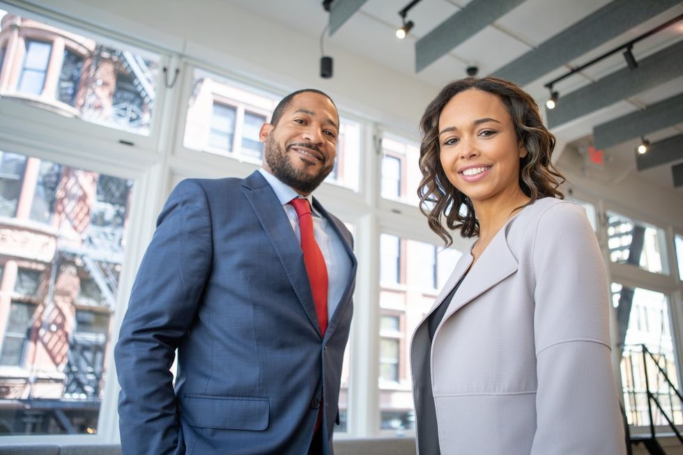 Professional woman at work stands with a professional man who referred her for a job