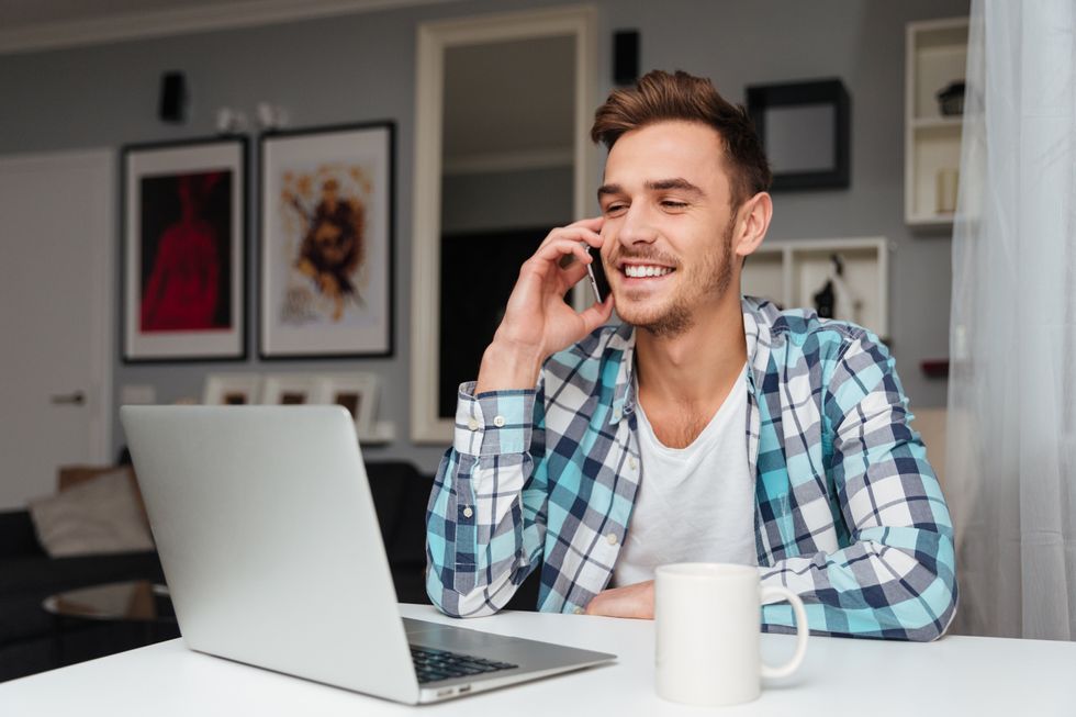 Happy man on laptop smiles during his phone interview