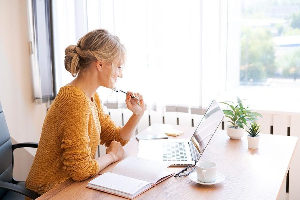 Woman on laptop thinks about what she's going to write