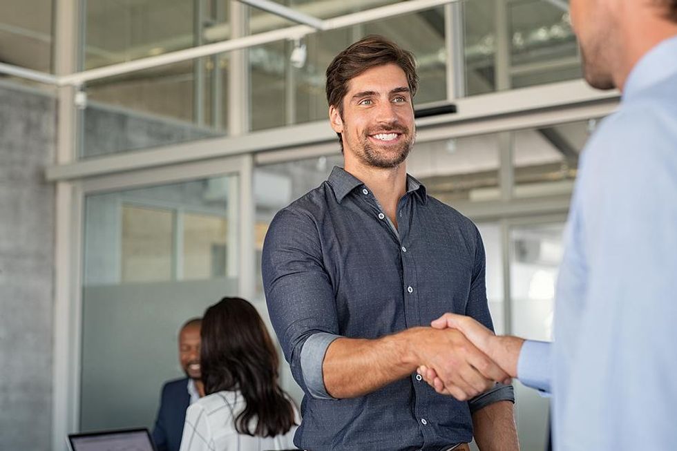 Man talks to a coworker and shakes his hand