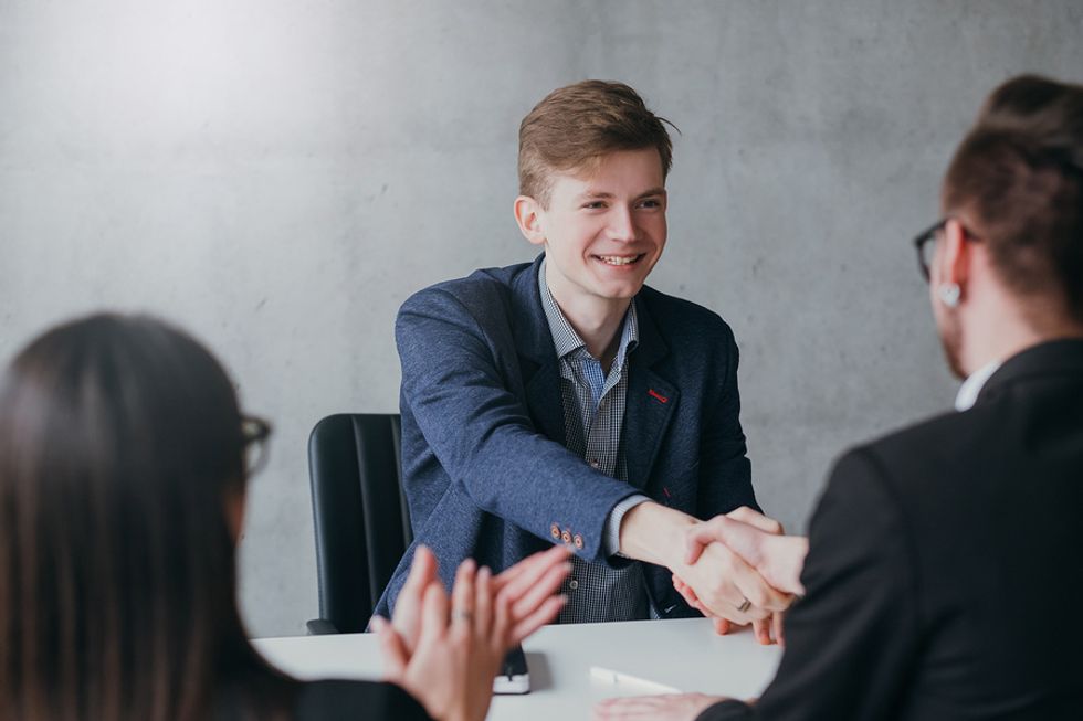 Young professional shakes hands with the hiring manager after accepting his first job offer at the end of an interview