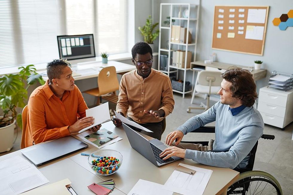 Diverse group of professionals/coworkers listen and talk to each other during a work meeting