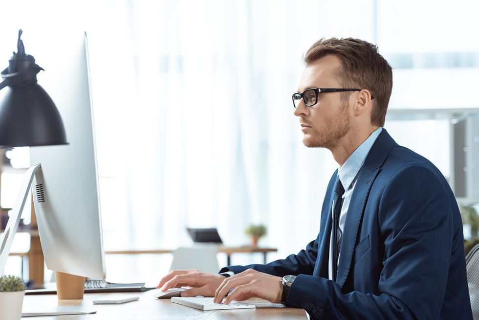 Man on computer enrolling in a leadership course to sharpen his leadership skills and climb the ladder at work