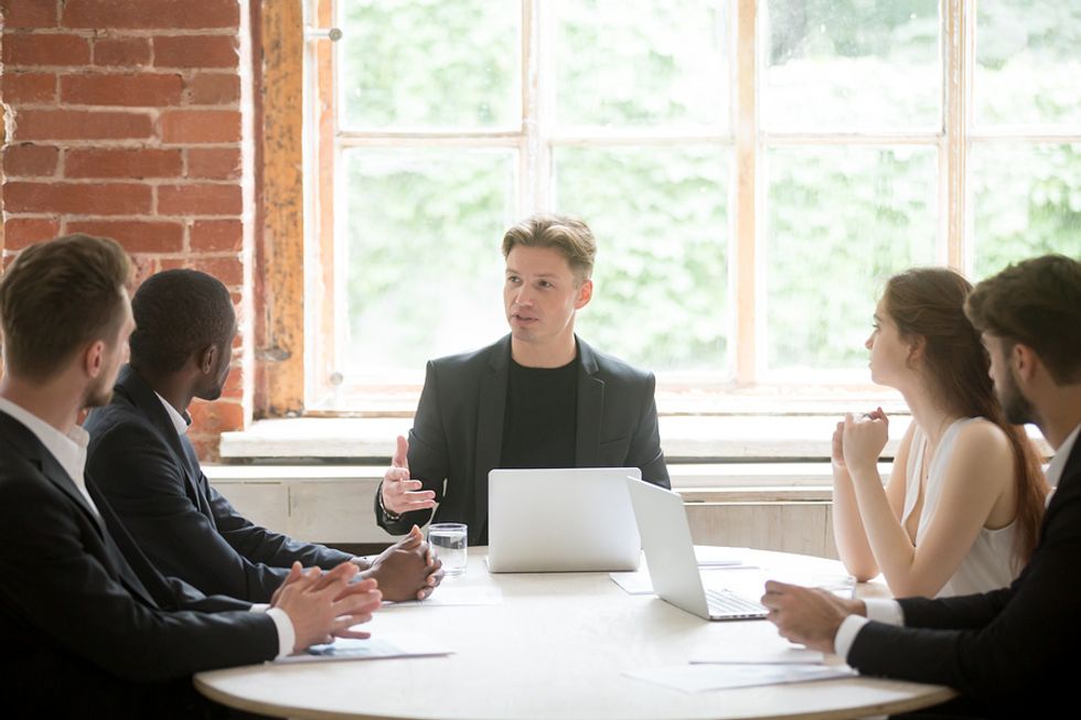 Man sharpening his leadership skills by delegating work to his team at work during a meeting