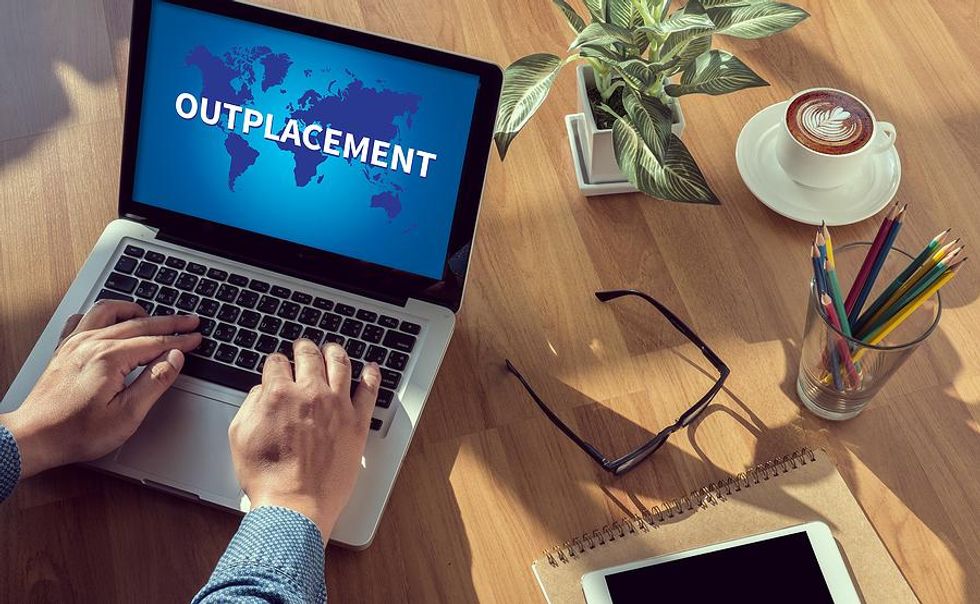 Laid-off employee on laptop uses outplacement services in their job search