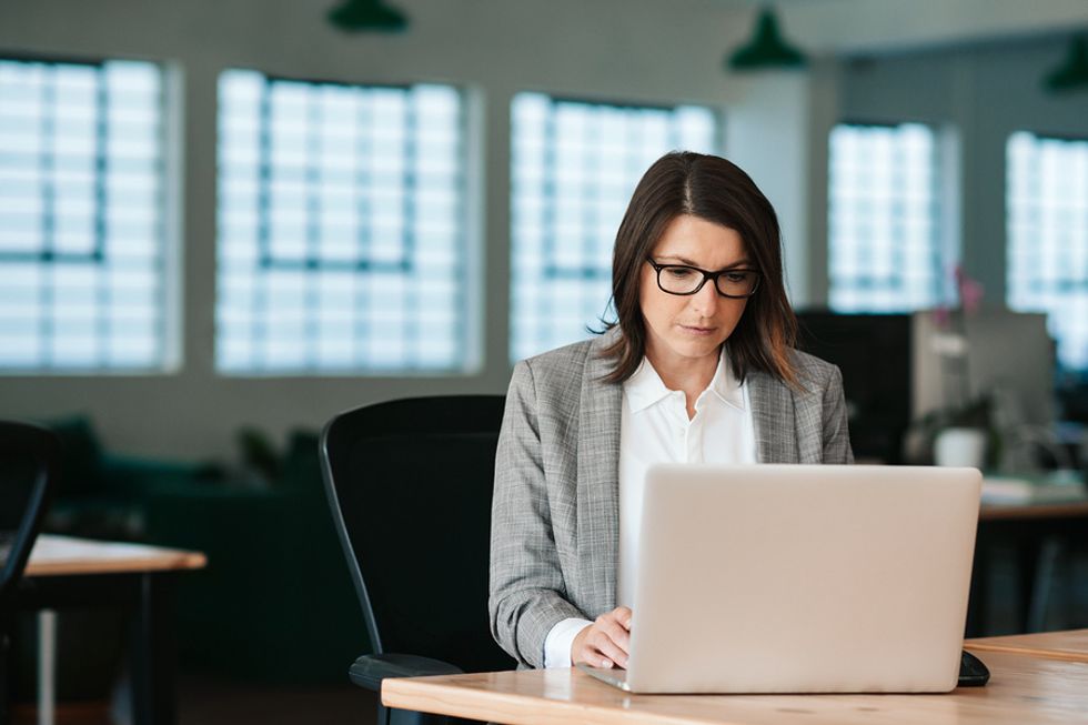 Business woman on laptop sitting at her desk and focusing on her most important tasks at work