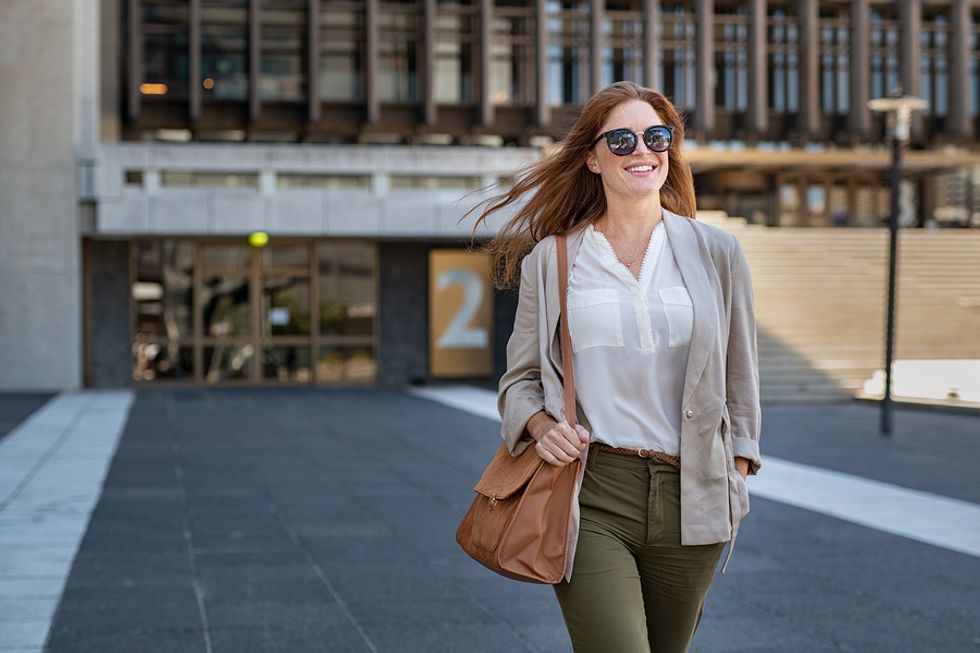 Smiling young female worker walking into work on her first day at a new office