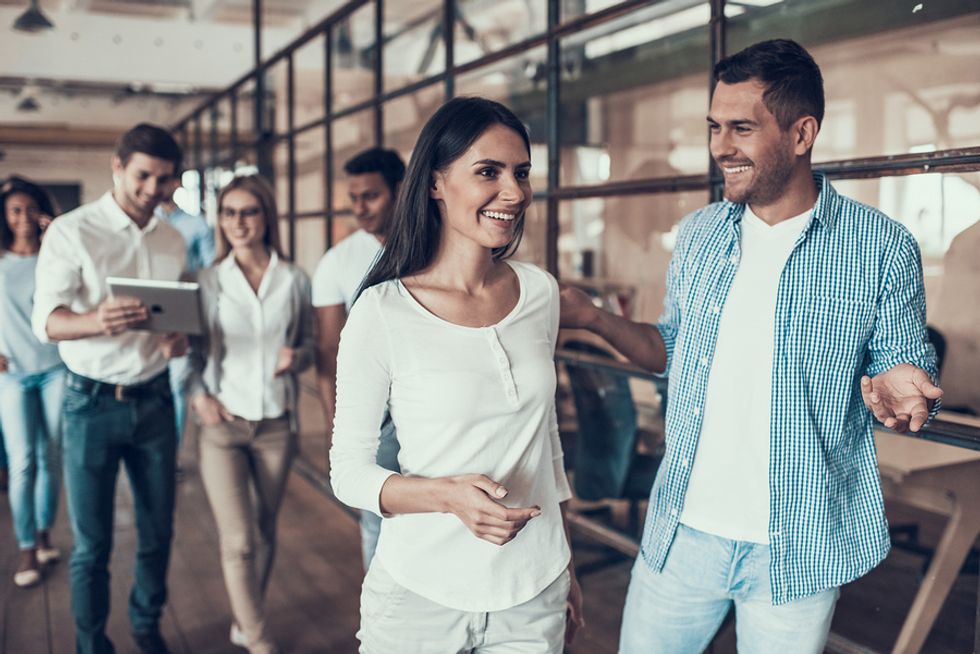 New female employee having a positive attitude while being shown around the office by a coworker on her first day at work