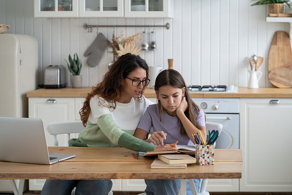 Working mom helps her child with homework while working remotely