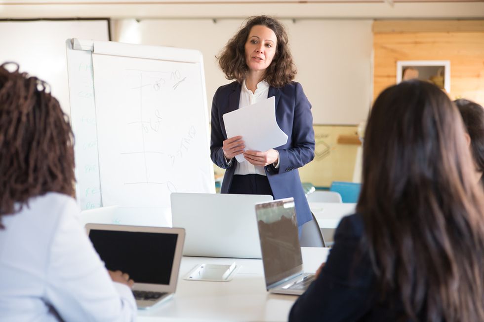 Leader/executive/manager/boss talks to her employees during a work meeting