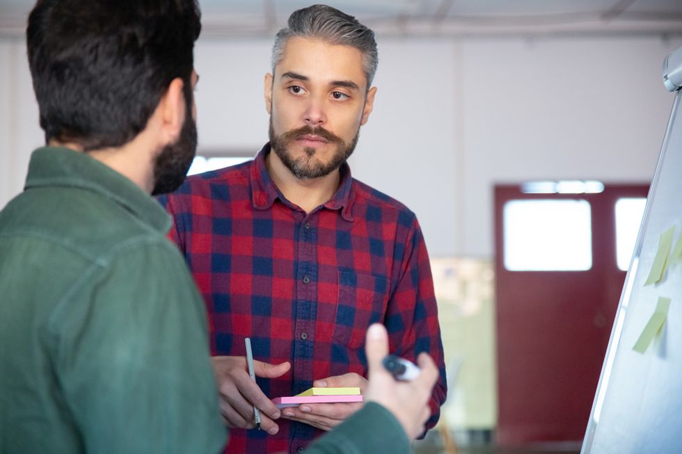 Man listens to his coworker during a meeting and tries to resolve a conflict