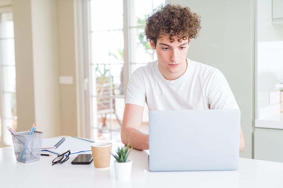 Young man on laptop properly optimizing his LinkedIn profile so it gets more views from employers