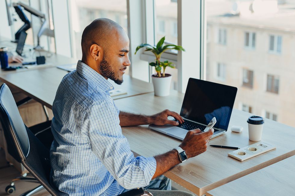 Man on laptop checks his phone before a job interview