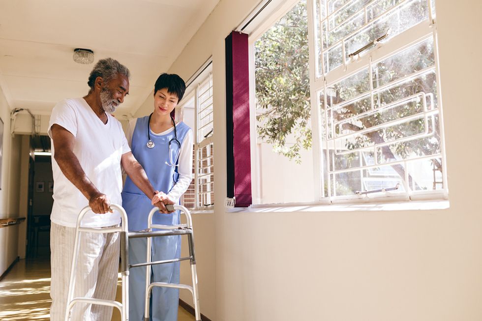 Nurse helps a man with a walker