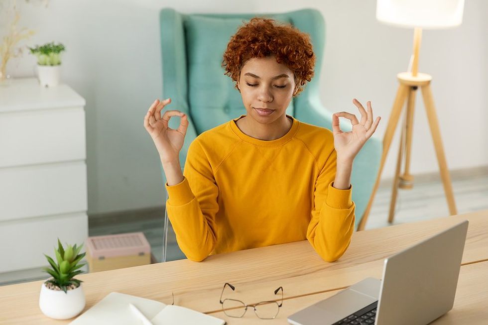 Woman meditates/calms herself down at work to manage stress