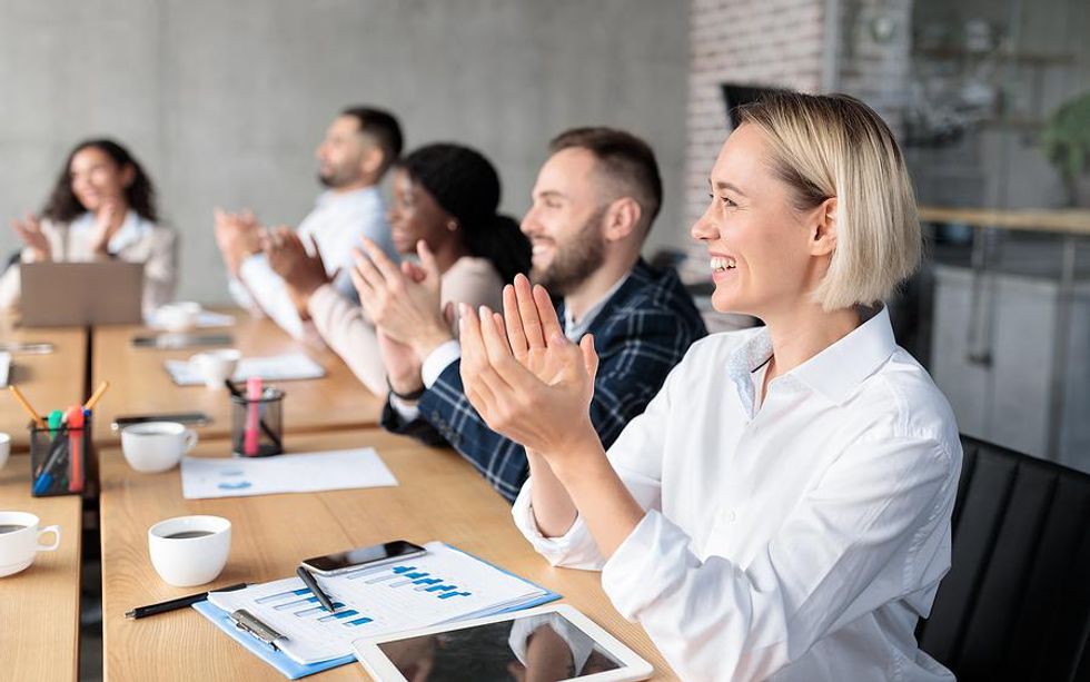 Happy/successful woman claps after a presentation during a work meeting