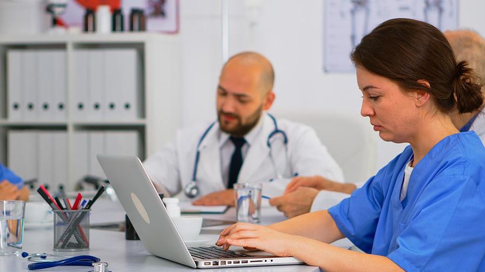 Medical assistant takes notes during a work meeting