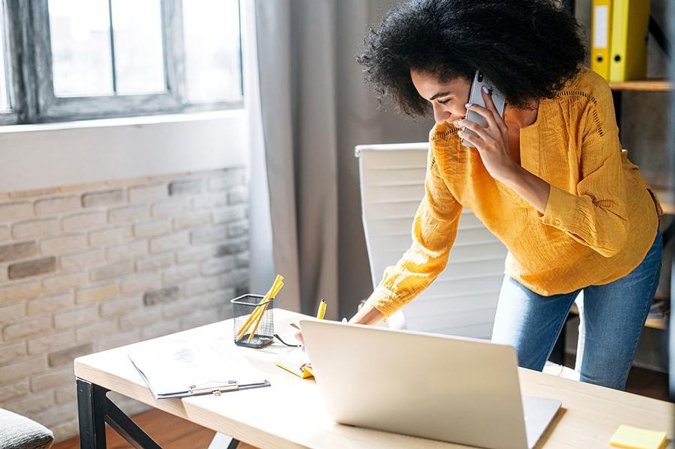 Happy woman on laptop and phone works toward her career goals