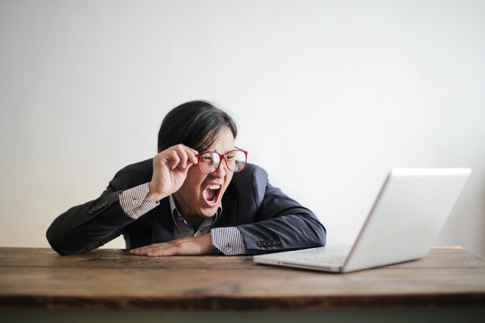 Angry man looks at common storytelling mistakes on his laptop