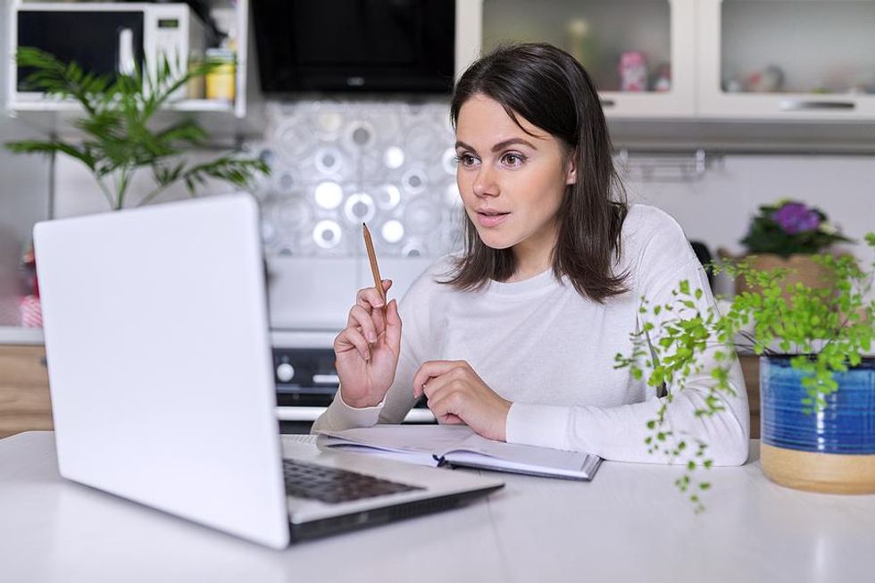 Job seeker on laptop takes notes while creating her interview bucket list