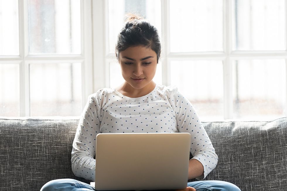 Unemployed young woman on laptop takes advantage of her free time by updating her resume and learning new skills