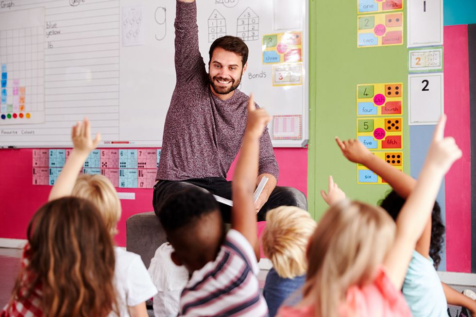 Young elementary school teacher reads a book to the class